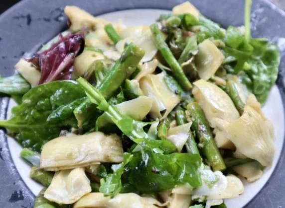 A plate with sliced green vegetables and white cheese or sauce.