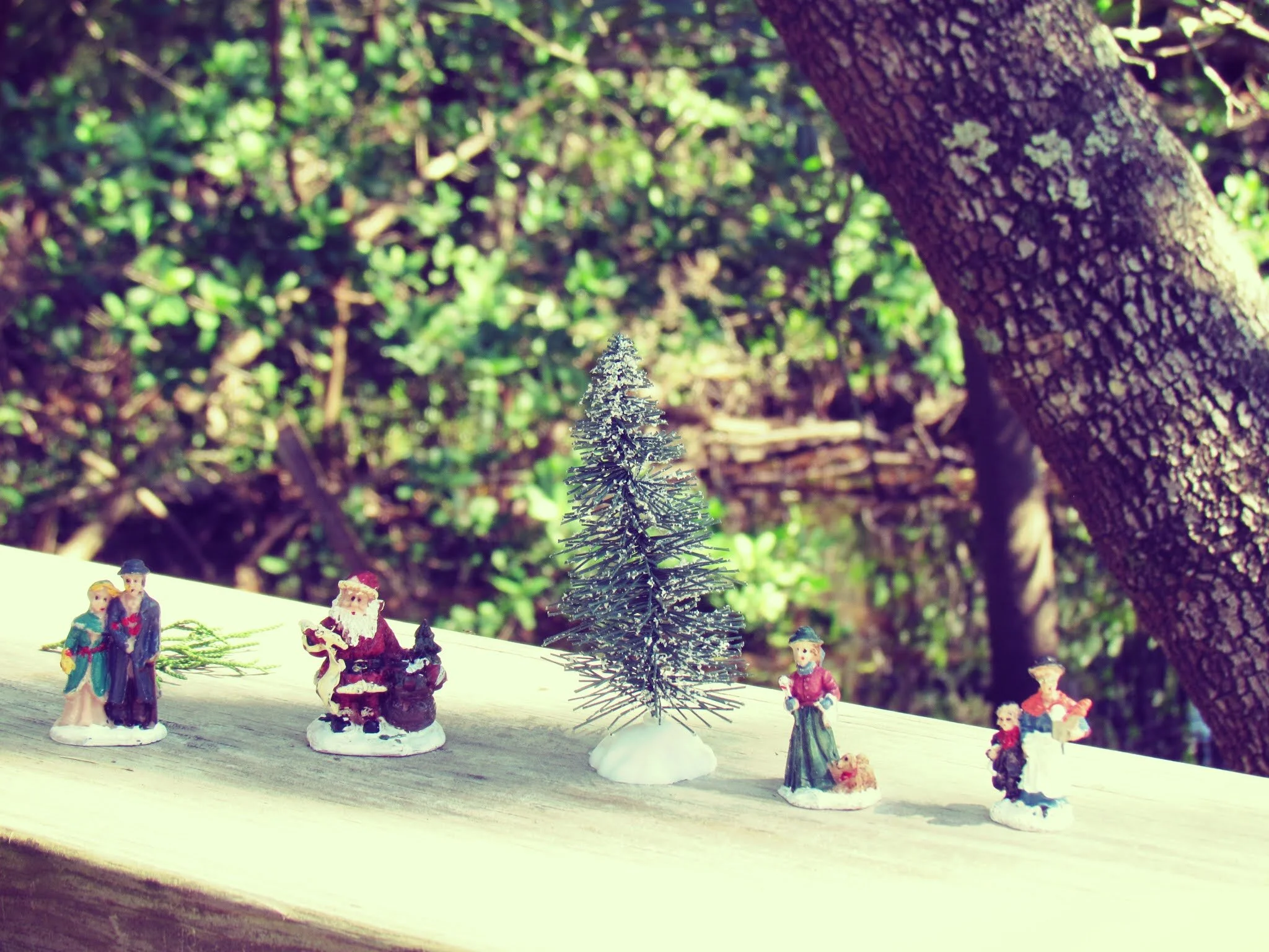 A collection of Christmas figurines and Christmas tree on a boardwalk in nature
