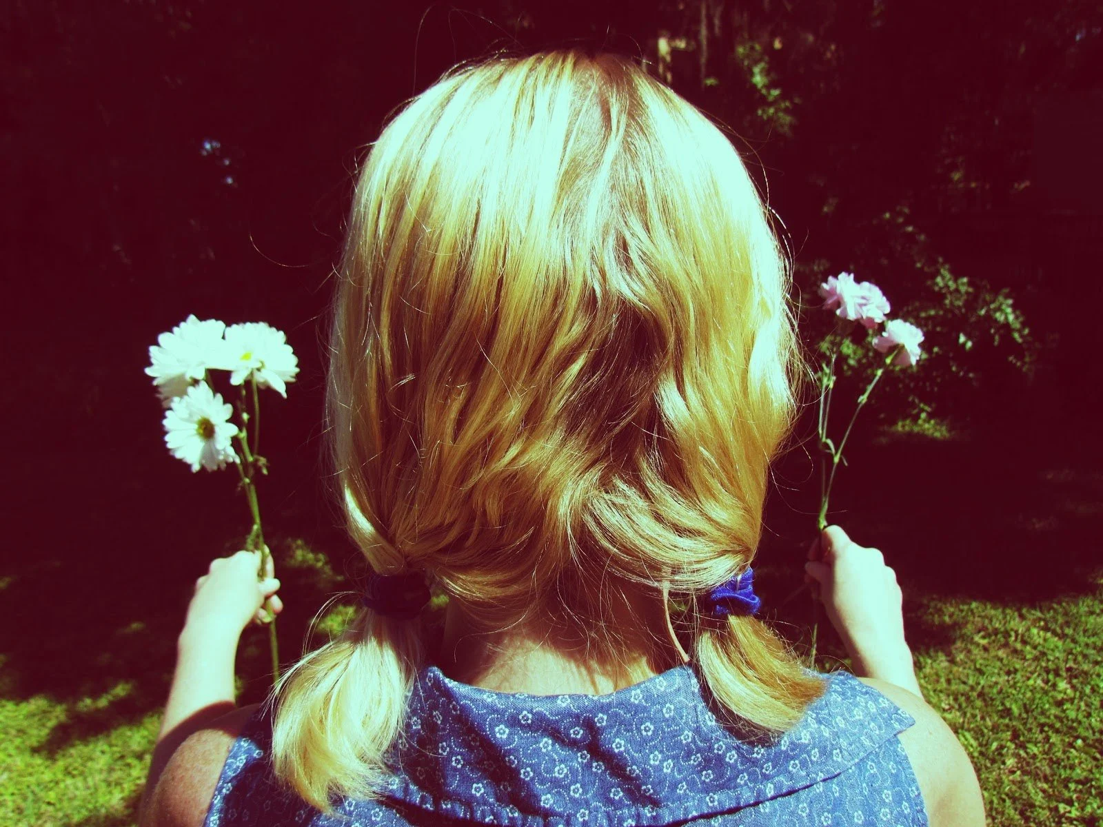 A woman with pigtails holding flowers in each hand backwards