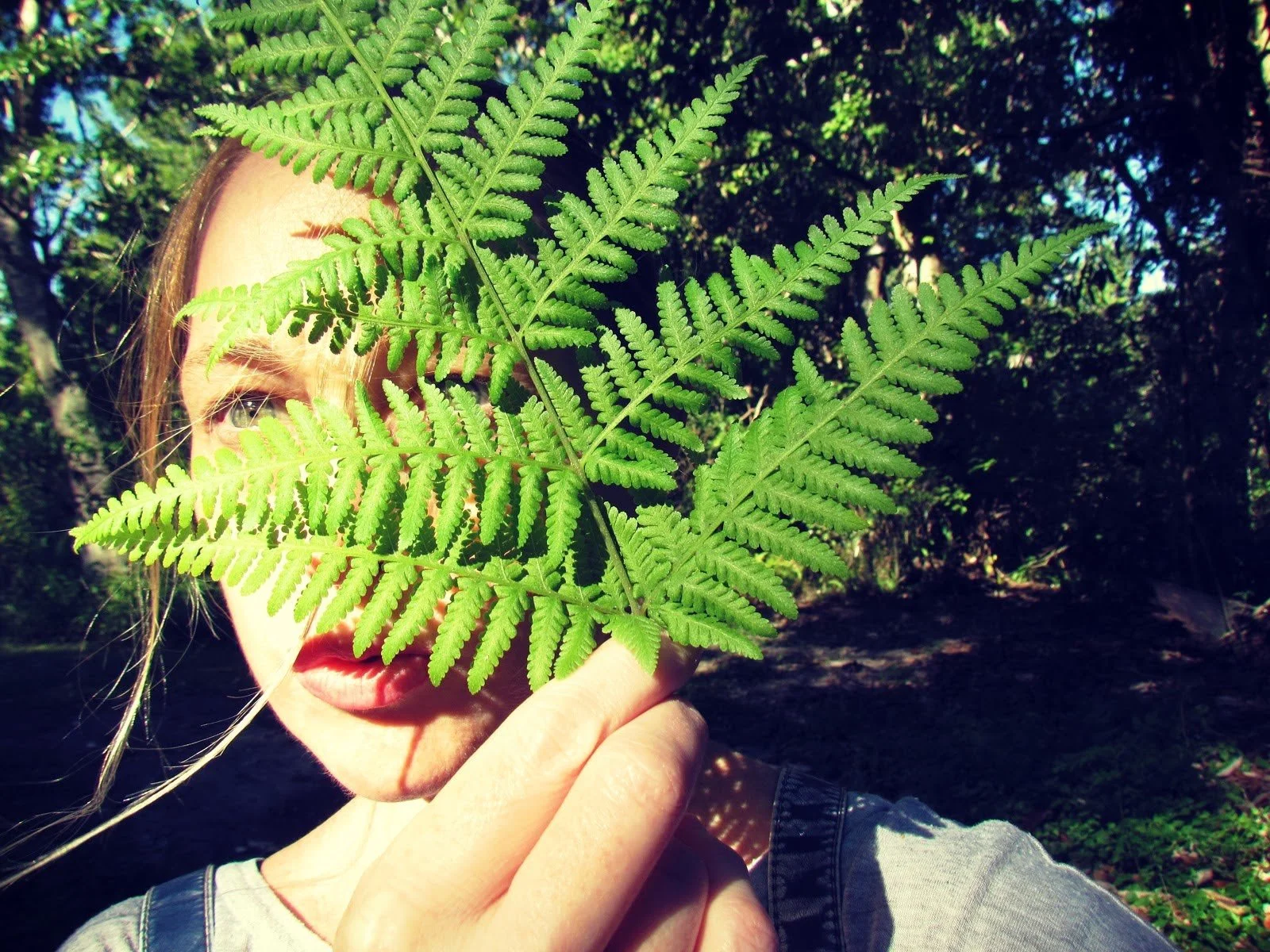 A woman hiking in the forest disguised by a fern plant