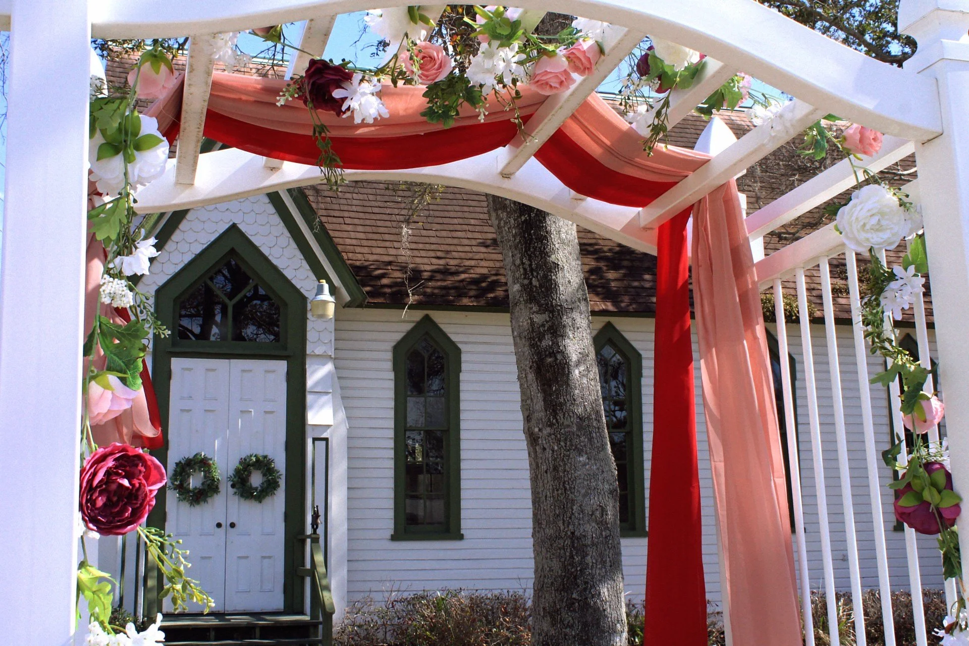 A cute little wedding chapel decorated in red and pink ribbons and flowers