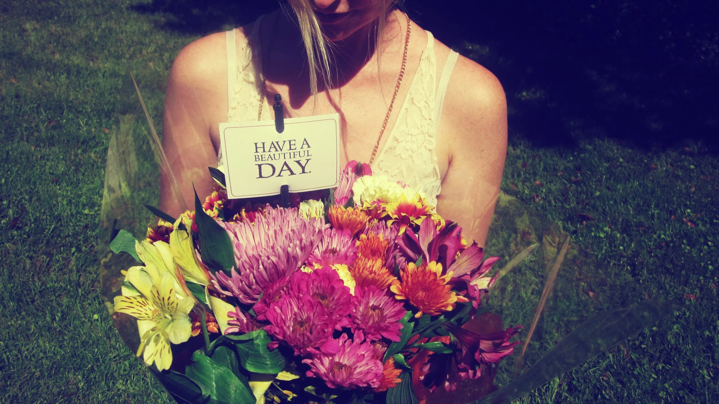 A woman holding a bouquet of spring flowers in the backyard with dark green grass