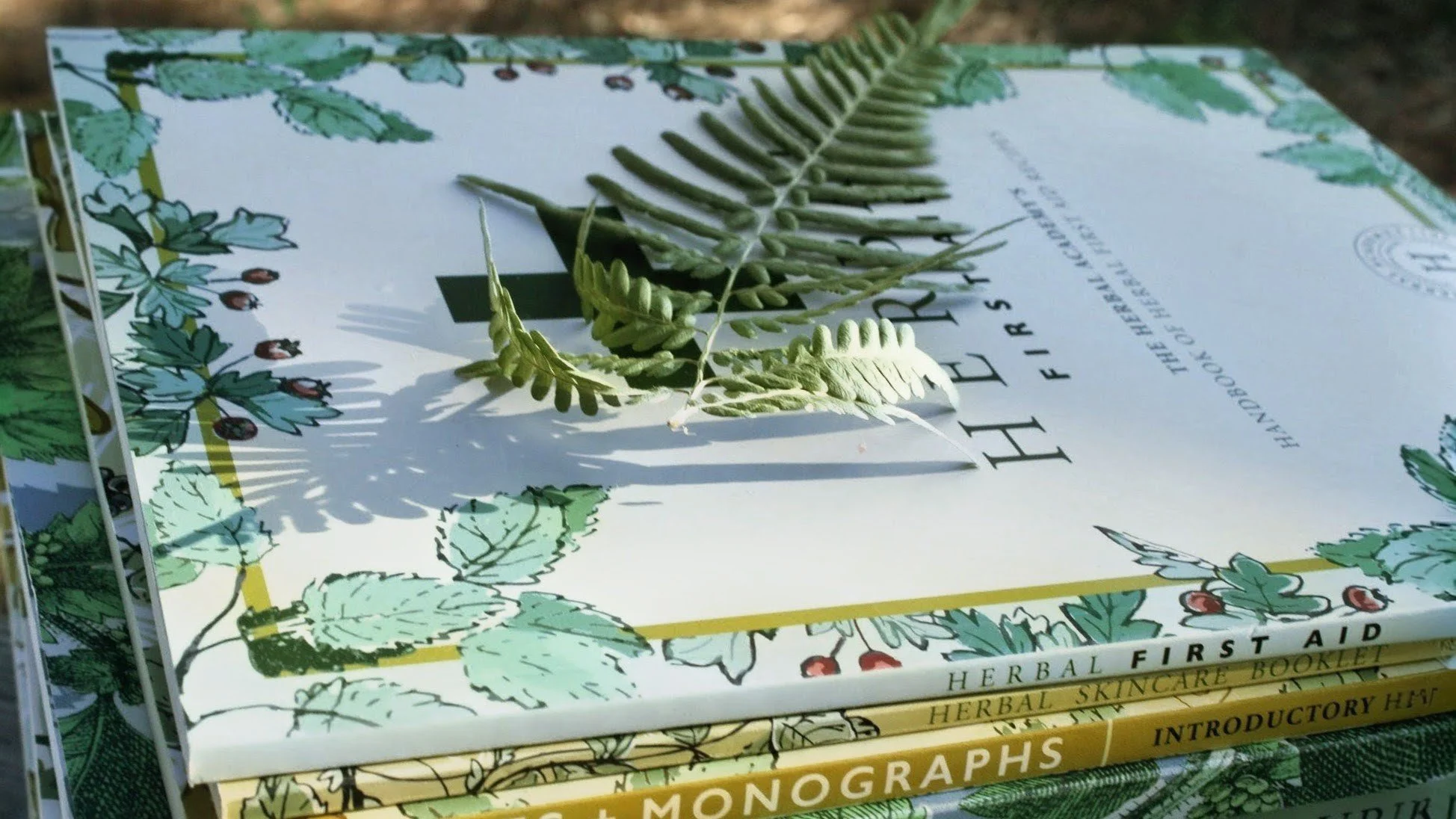 A stack of Herbalism coursebooks from Herbal Academy