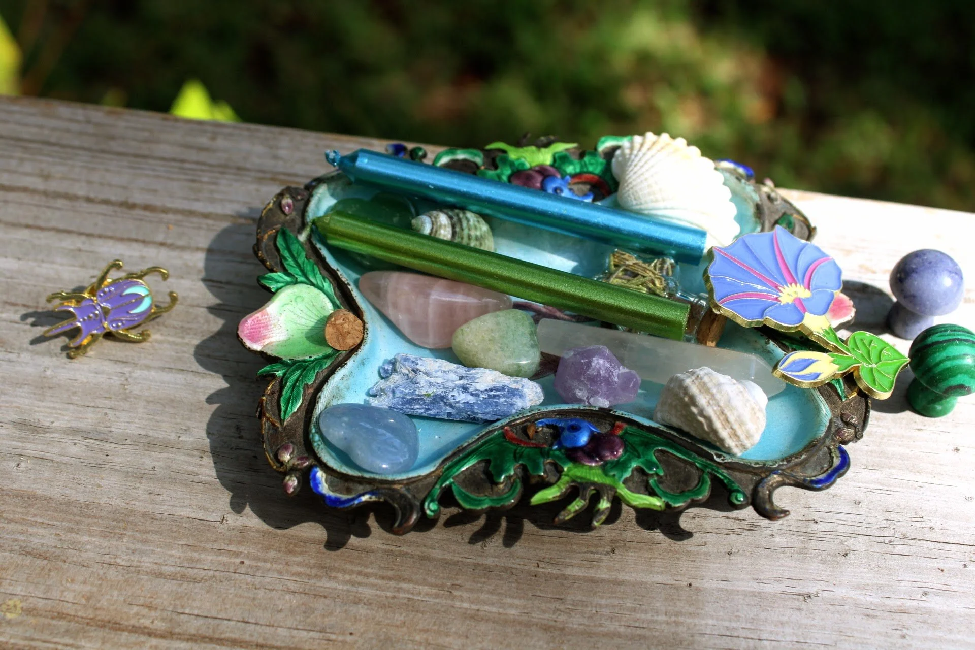 A mermaid-inspired dish that holds crystals, candles, and lapel pins with a sea theme