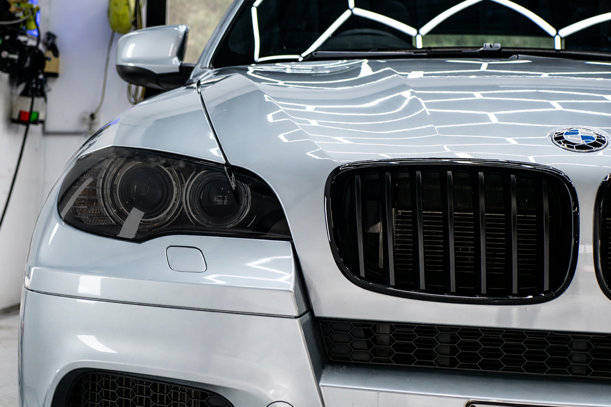 Close-up of the front of a silver BMW car showing the headlights, kidney grille, and part of the hood.