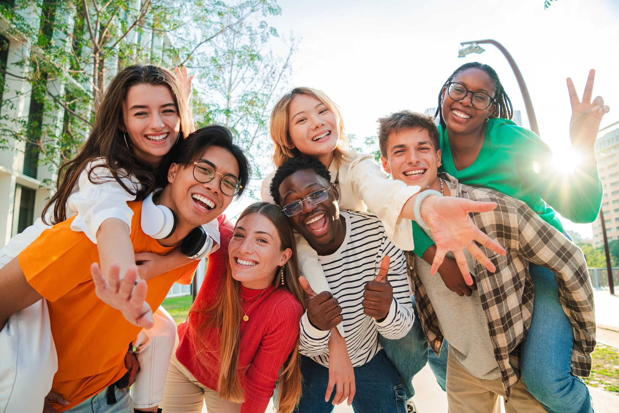 Diverse group of teens smiling and spending time together outside, reflecting connection and emotional well being.