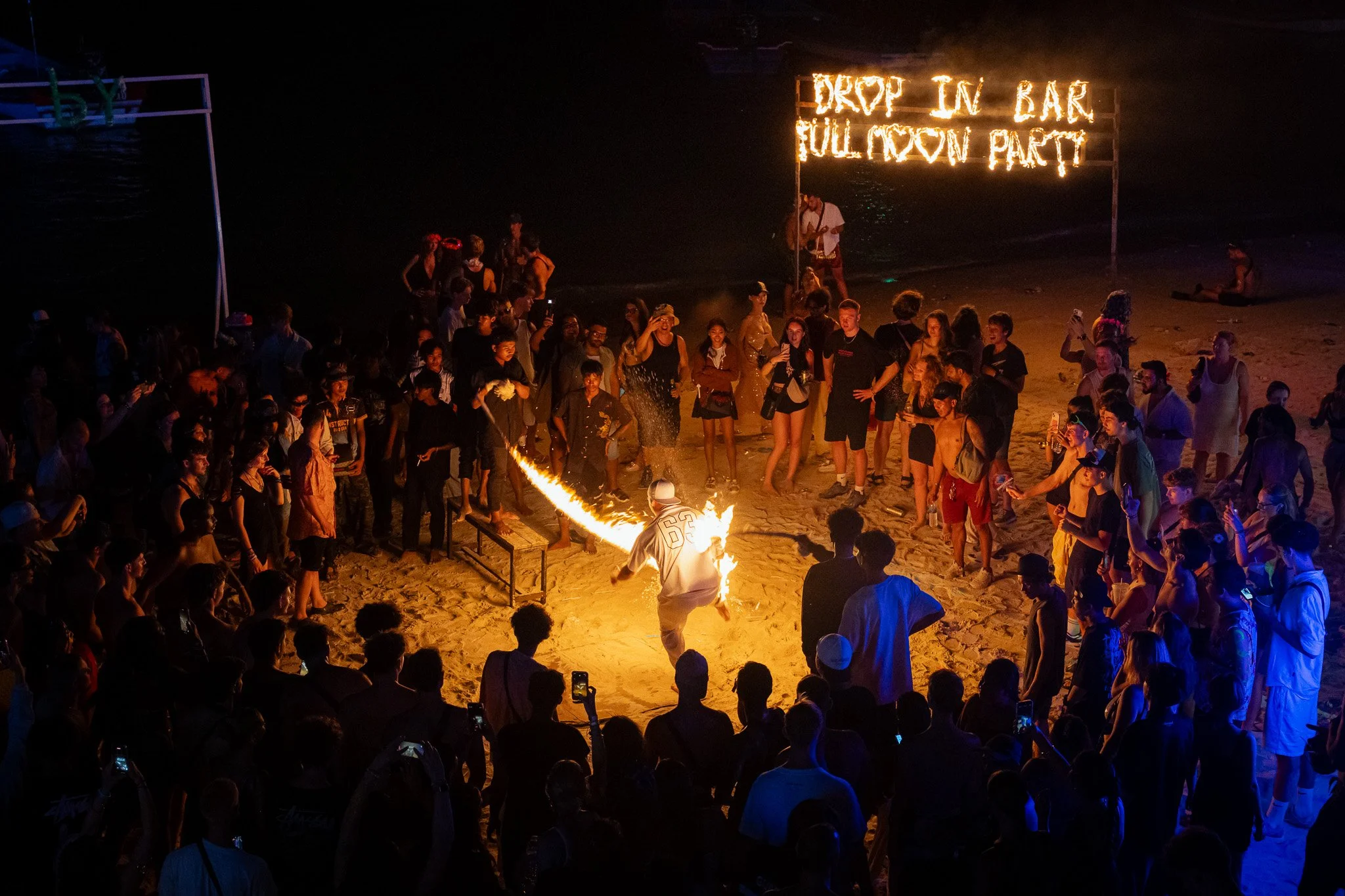 Spectators watch a tourist catch the flames of a jump rope at the Full Moon Party.