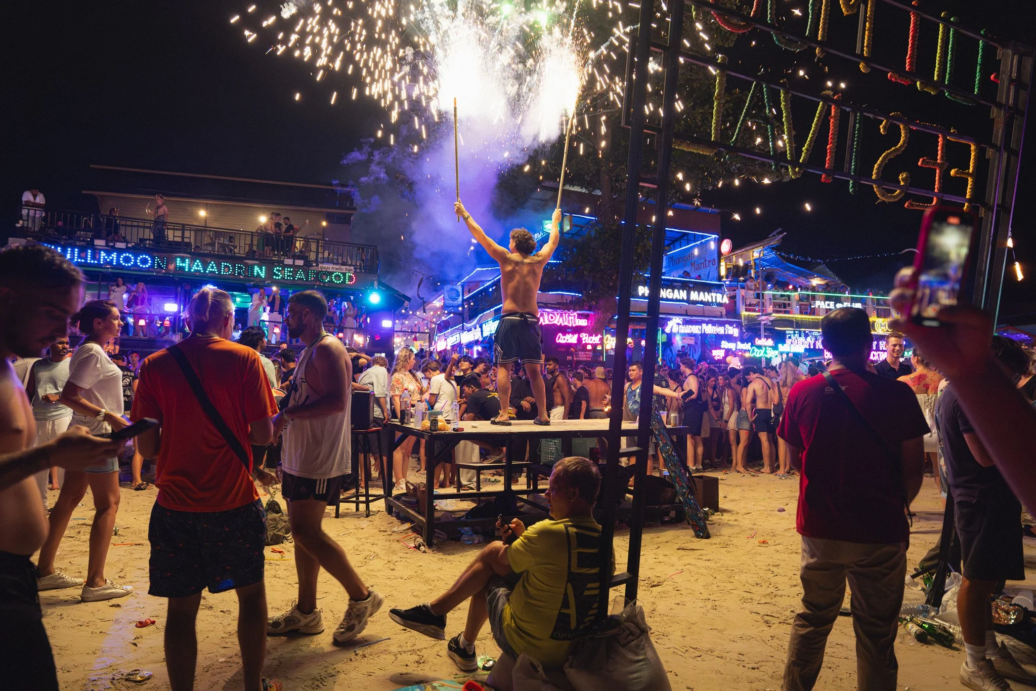 A man with handheld fireworks poses for a photo on Haan Rin beach.