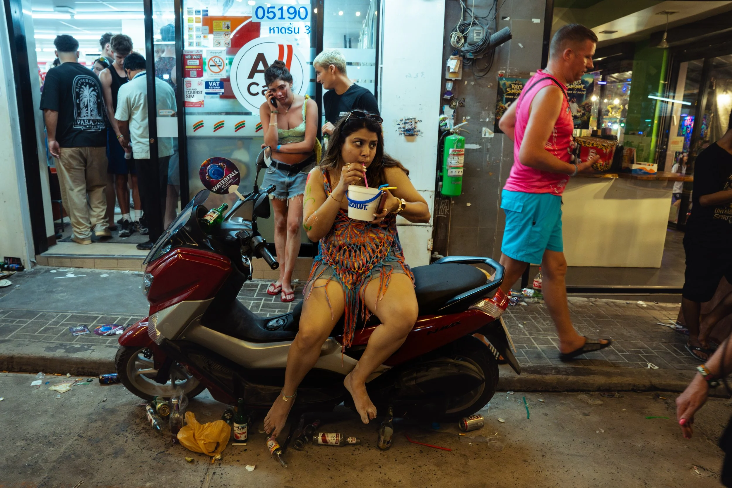 A tourist sips a bucket of alcohol outside the 7-Eleven on Haan Rin beach.
