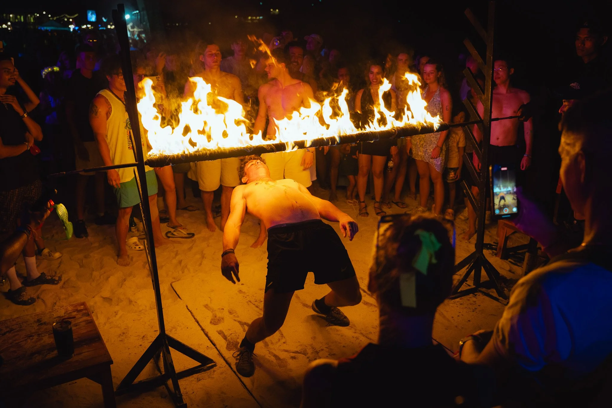 A tourist does the limbo under a flaming rod on Haan Rin beach.