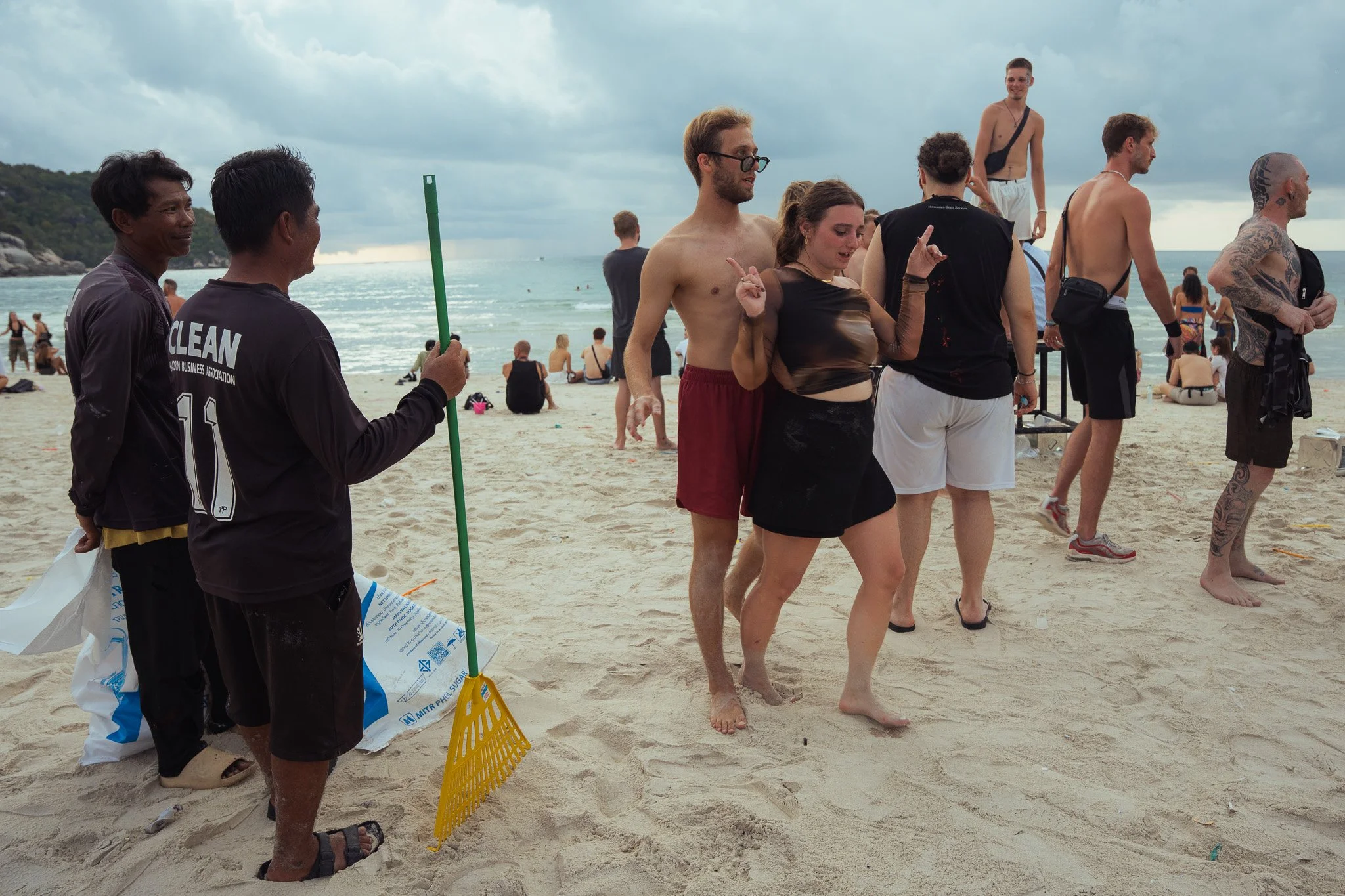 Thai beach cleaners watch with amusement as some tourists continue dancing in the daylight at dawn on Haan Rin beach.