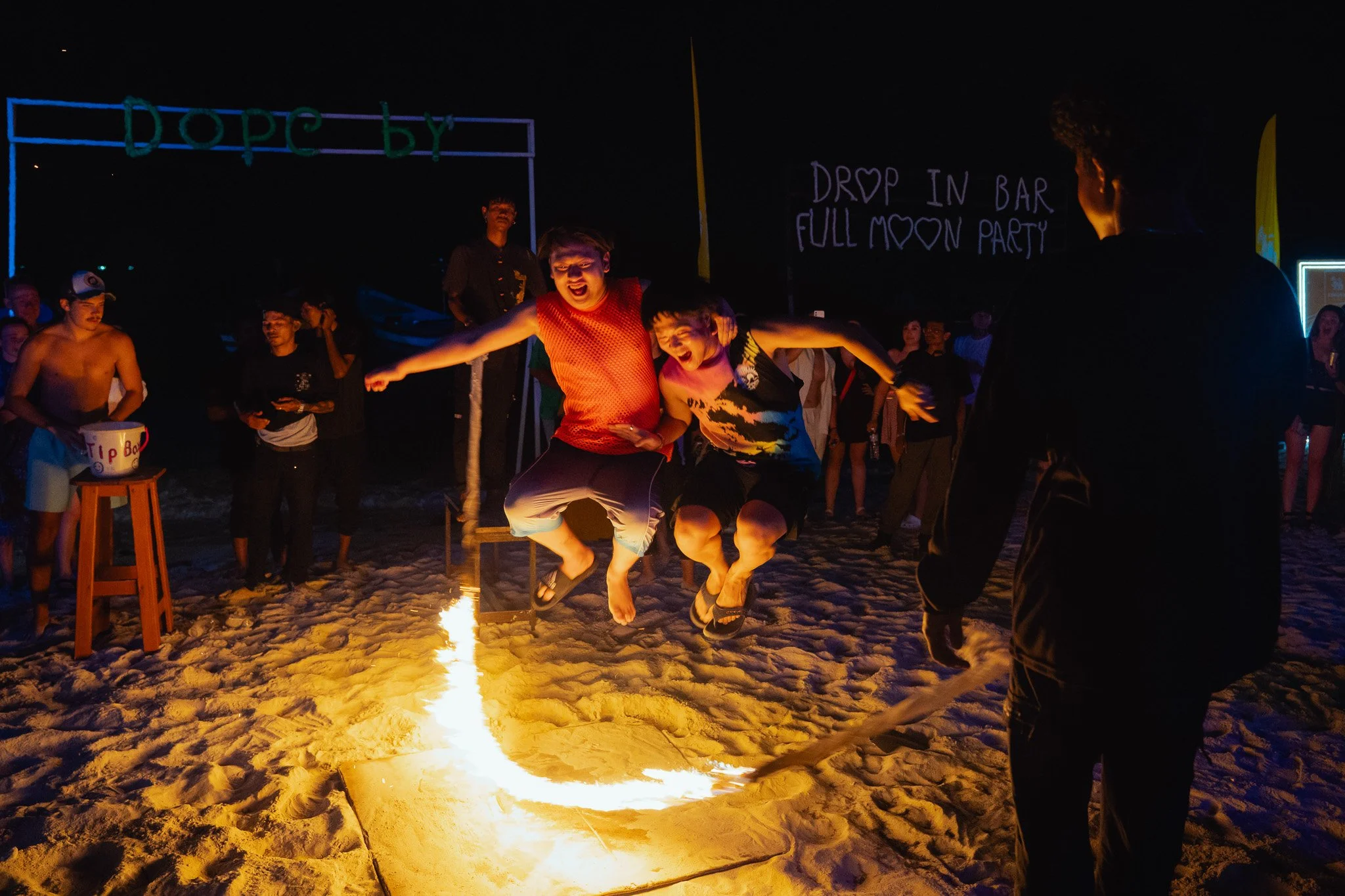 Two men express glee while jumping a flaming skipping rope at the Full Moon Party.