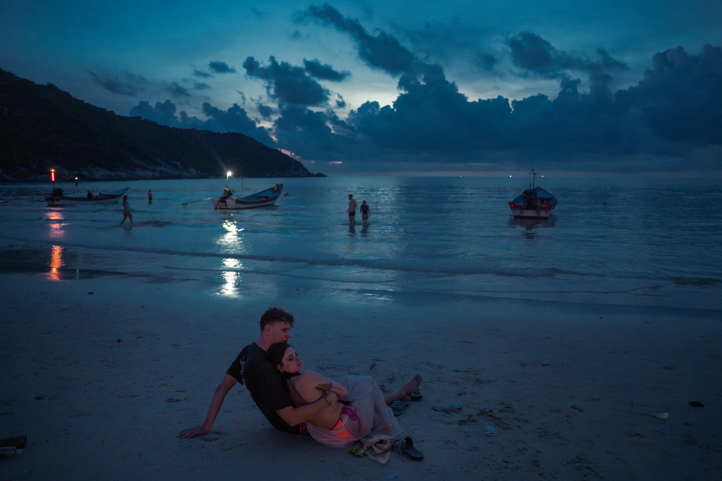 As dawn breaks, a couple watches the sunrise on the beach.