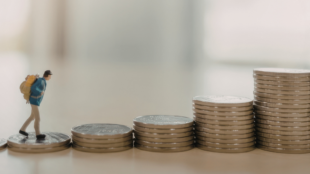 tiny person hikes up a an escalation of stacked coins