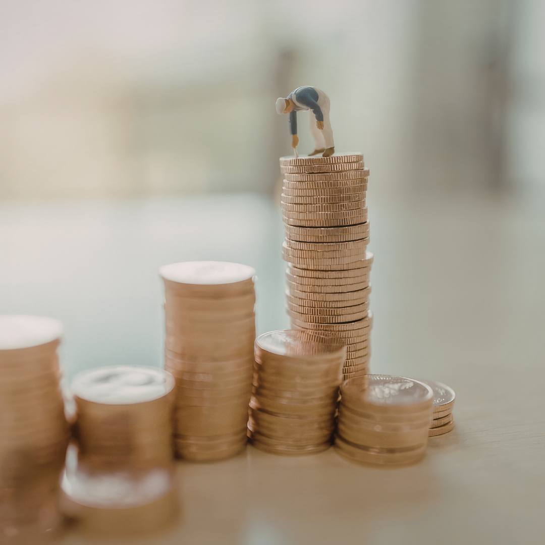 tiny construction worker on top of a stack of coins,