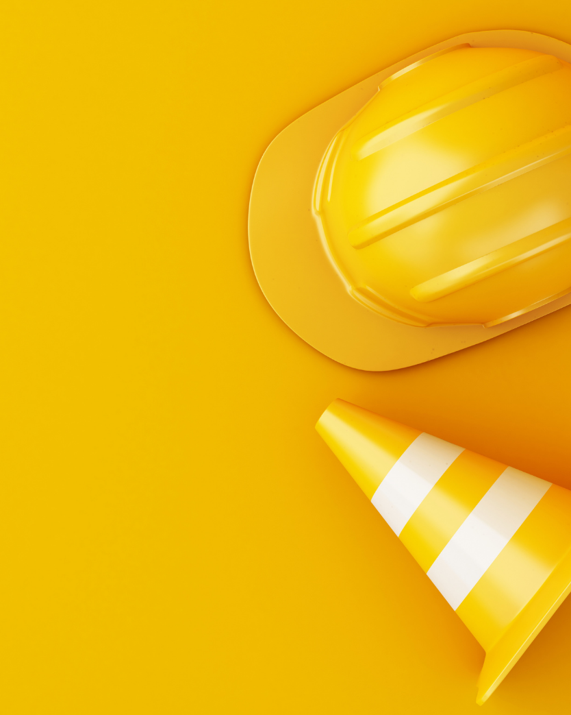yellow hard hat and warning pylon on the right side of image with a yellow background.