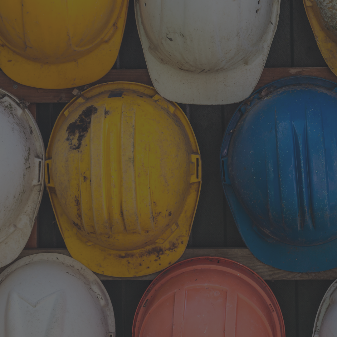 Muted image of weathered hard hats in yellow, red, white and blue