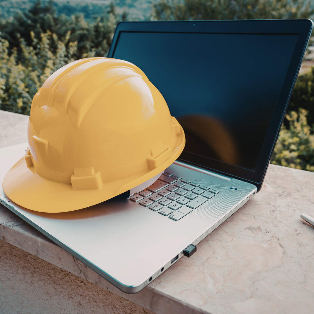 A hard hat sits atop an open laptop