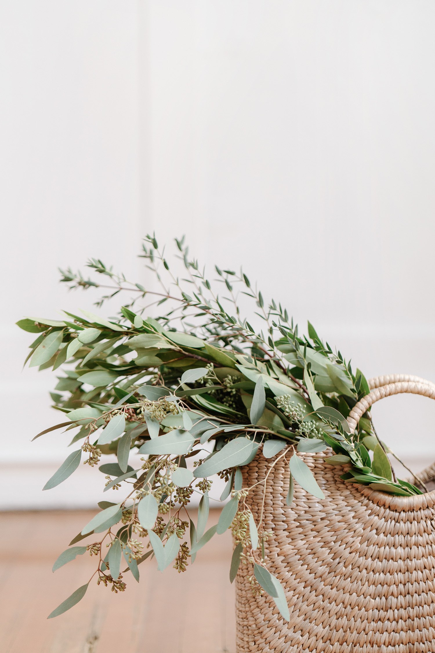 Light rattan basket filled with greenery as a home stylist accessory