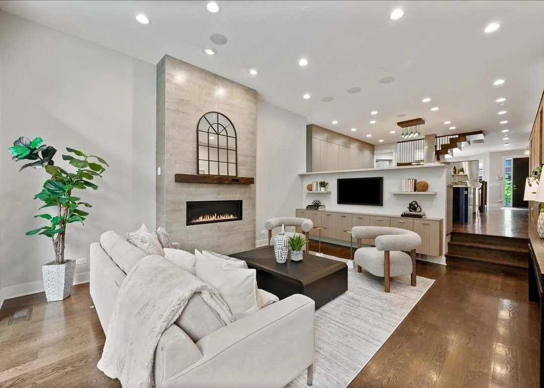 Modern living room with white sofa, potted plant, fireplace, TV, and wooden accents.
