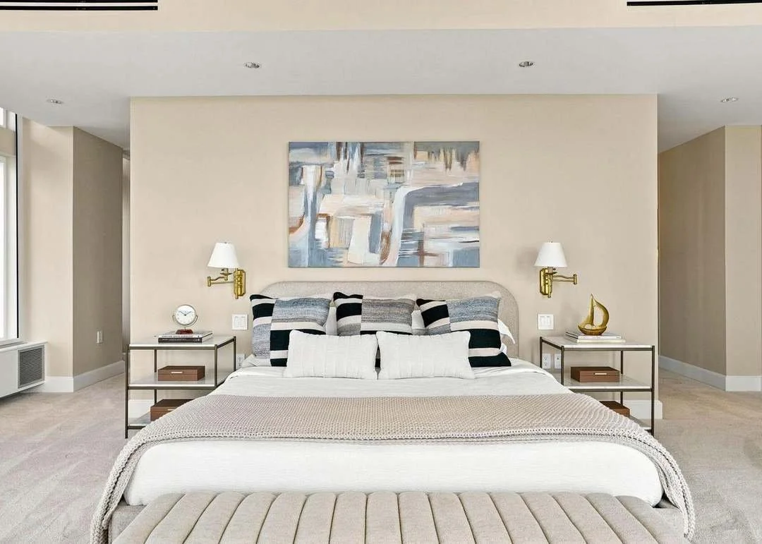 A bedroom with a large bed, two nightstands with lamps, pillows, and abstract artwork on the wall.
