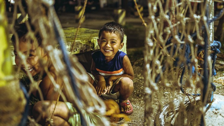 Un bambino sorride tra le catene di un ponte: fotografia di Walter Stolfi.