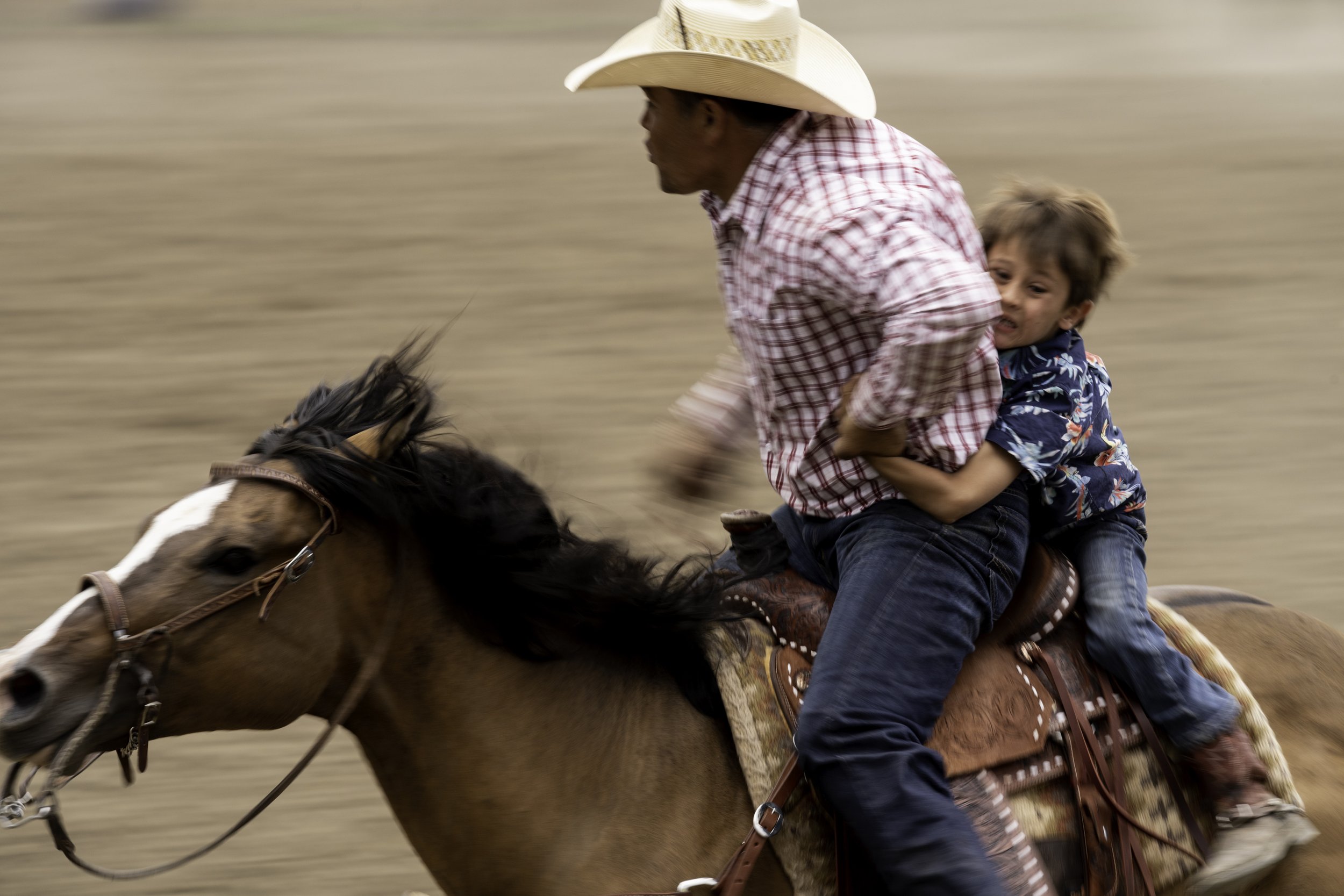  A boy holds on tight during the rescue race at the 99th Maverick Club Rodeo at The Maverick Club Rodeo Grounds in Cimarron, N.M. on July 4, 2022. The annual event is the longest running open rodeo in the Western United States beginning in 1923.  