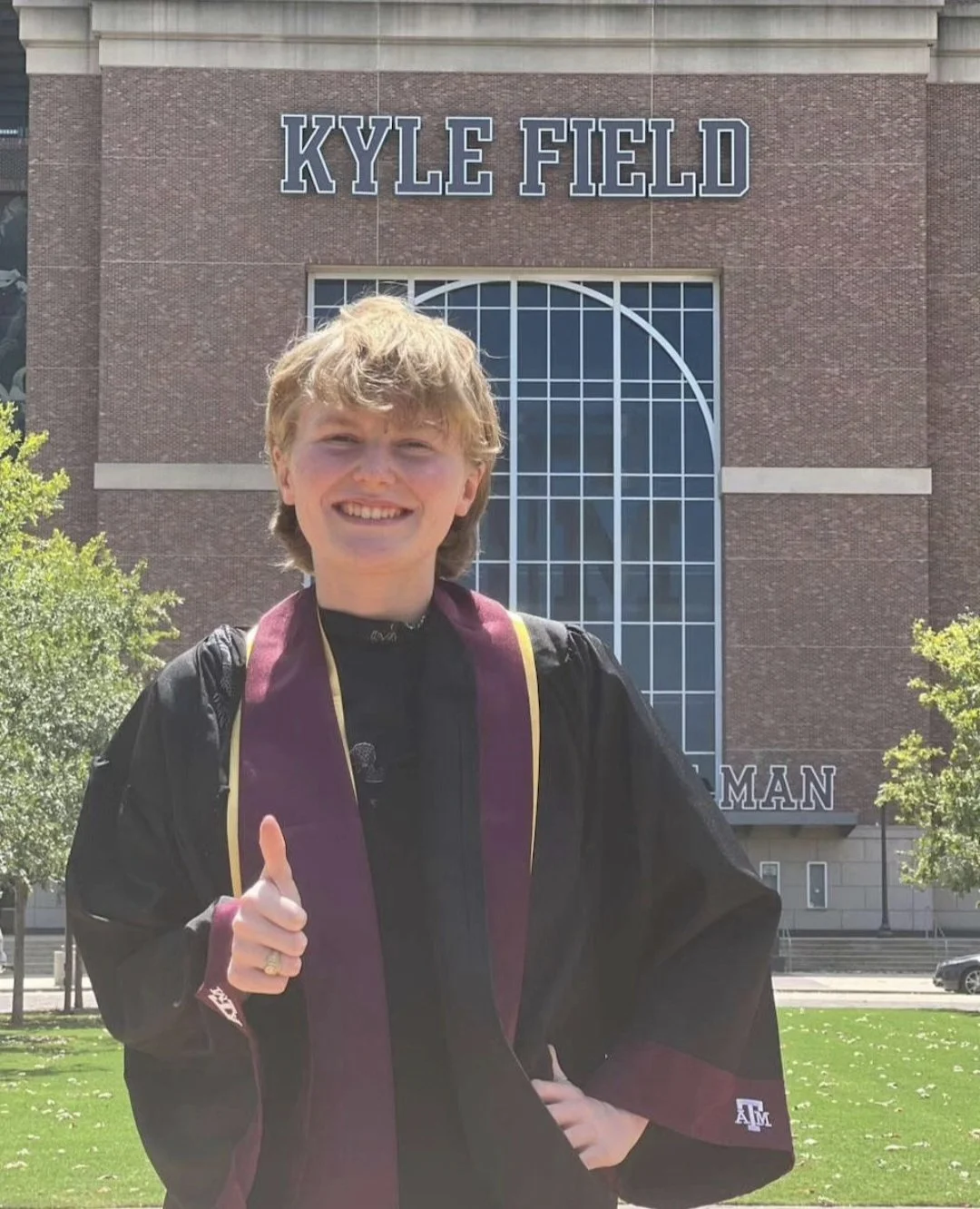 A woman standing in front of a building wearing graduation robes