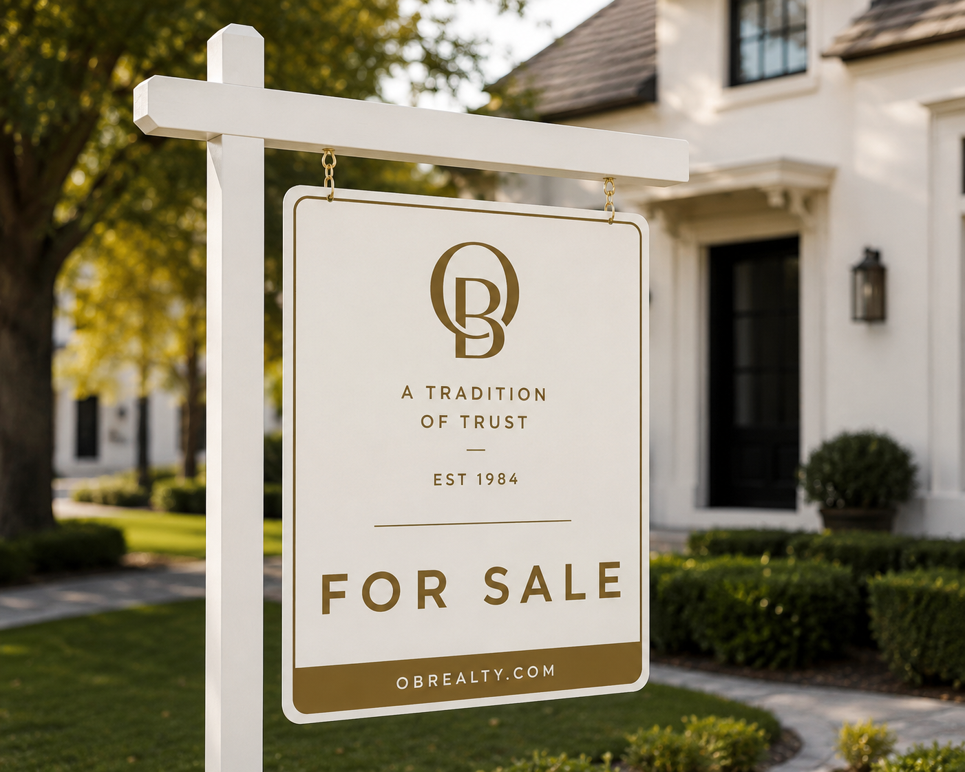 Real estate sign in front of a white house with black door, for sale by OBRealtY, established in 1984, with the slogan 'A tradition of trust.'