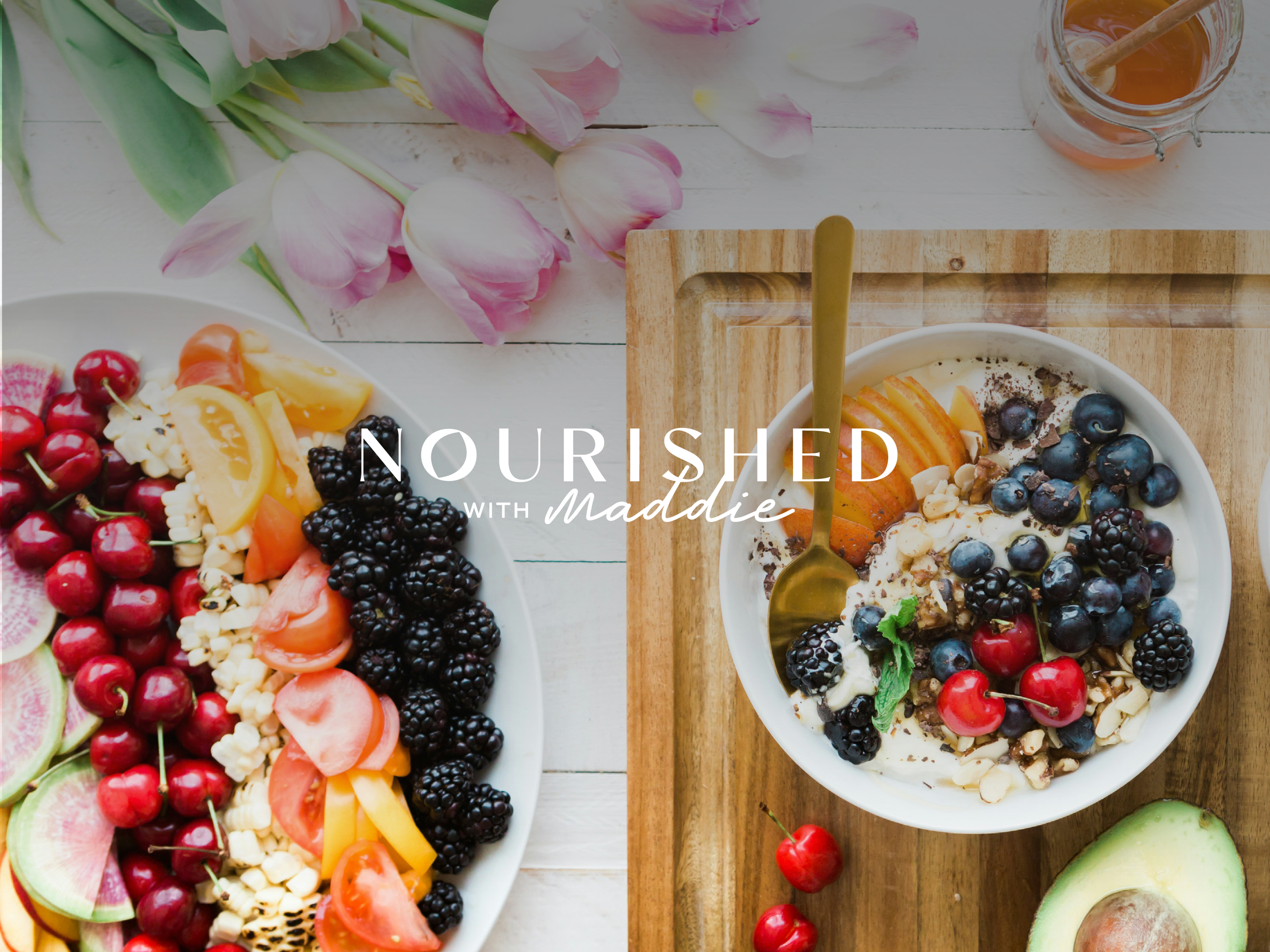 Healthy food display with a bowl of yogurt topped with berries, nuts, and fruit; a separate platter of colorful fruits and vegetables; avocado; honey jar; pink tulips; text 'NOURISHED with maddie.'