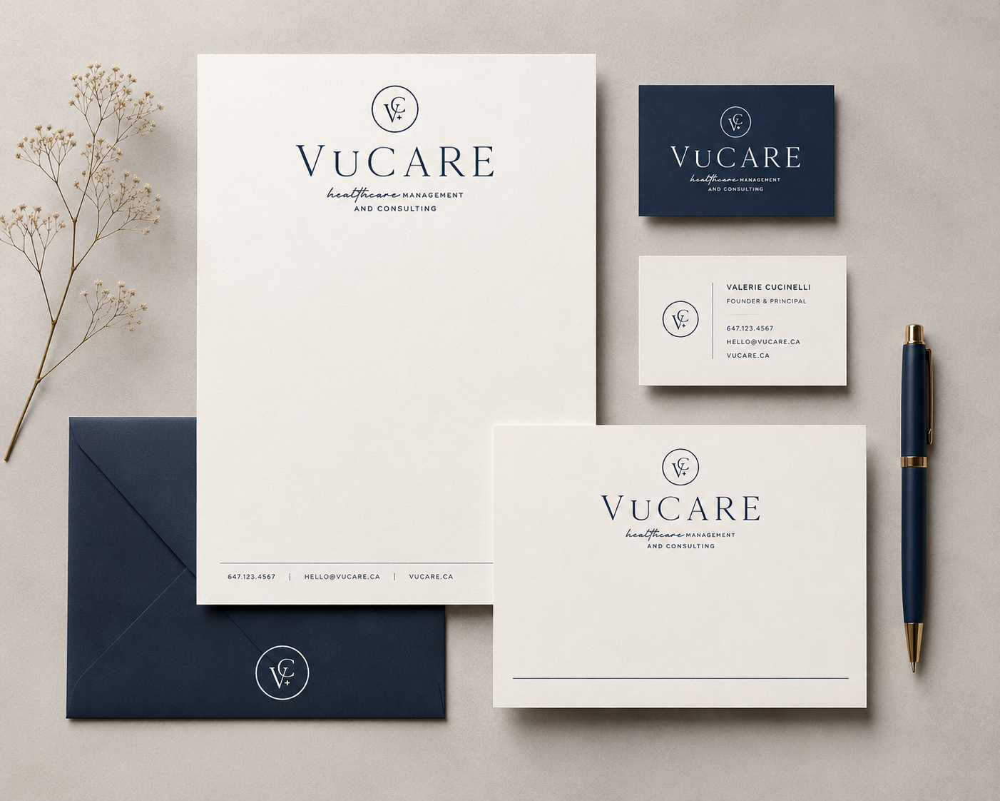 Business branding stationery set for VUCare, including letterhead, business card, envelope, and notepad, with a pen and decorative dried flowers on a neutral background. The color scheme is navy blue and white.