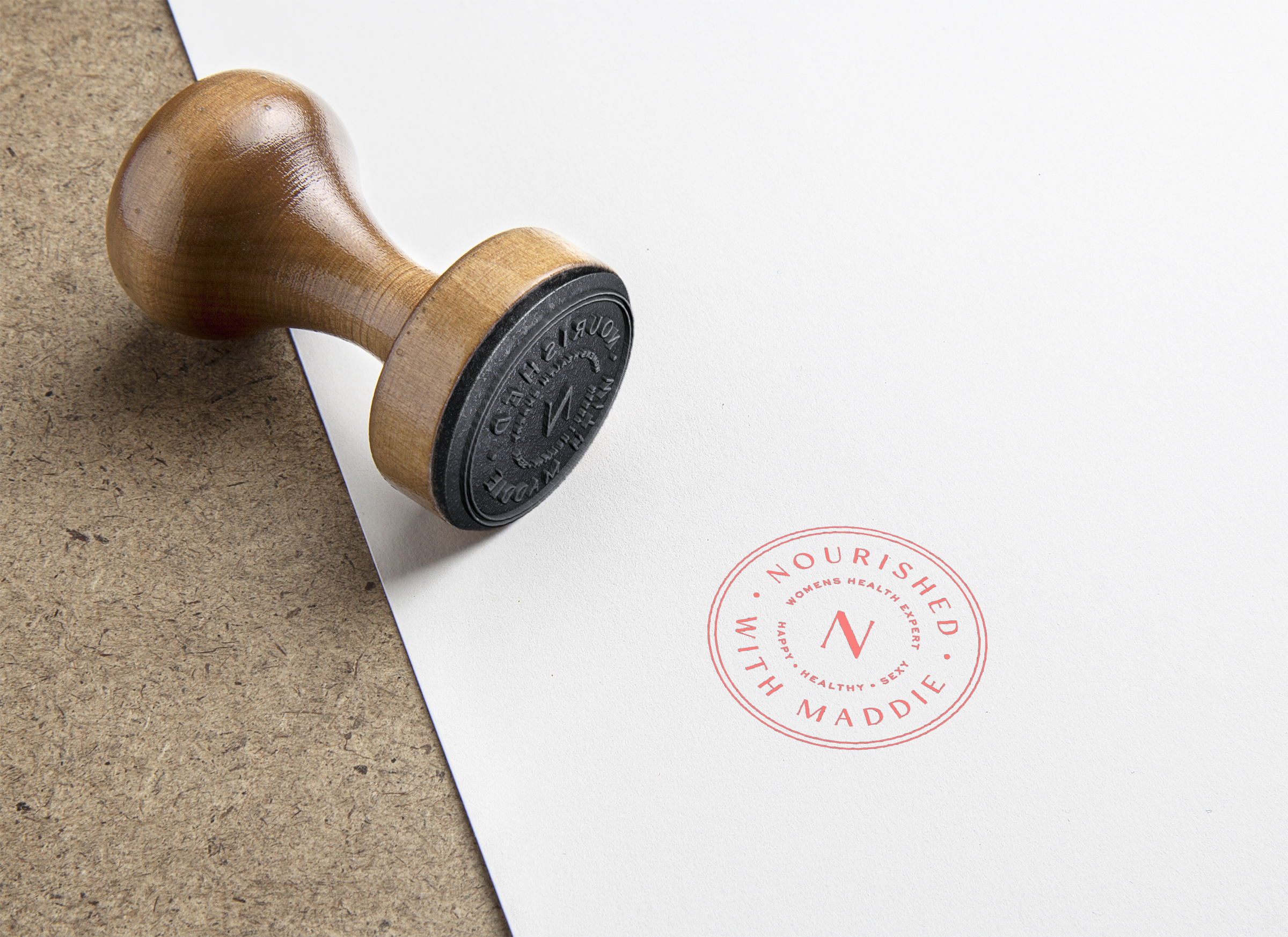 Wooden stamp and stamped impression with logo and text "Nourished with Maddie"
