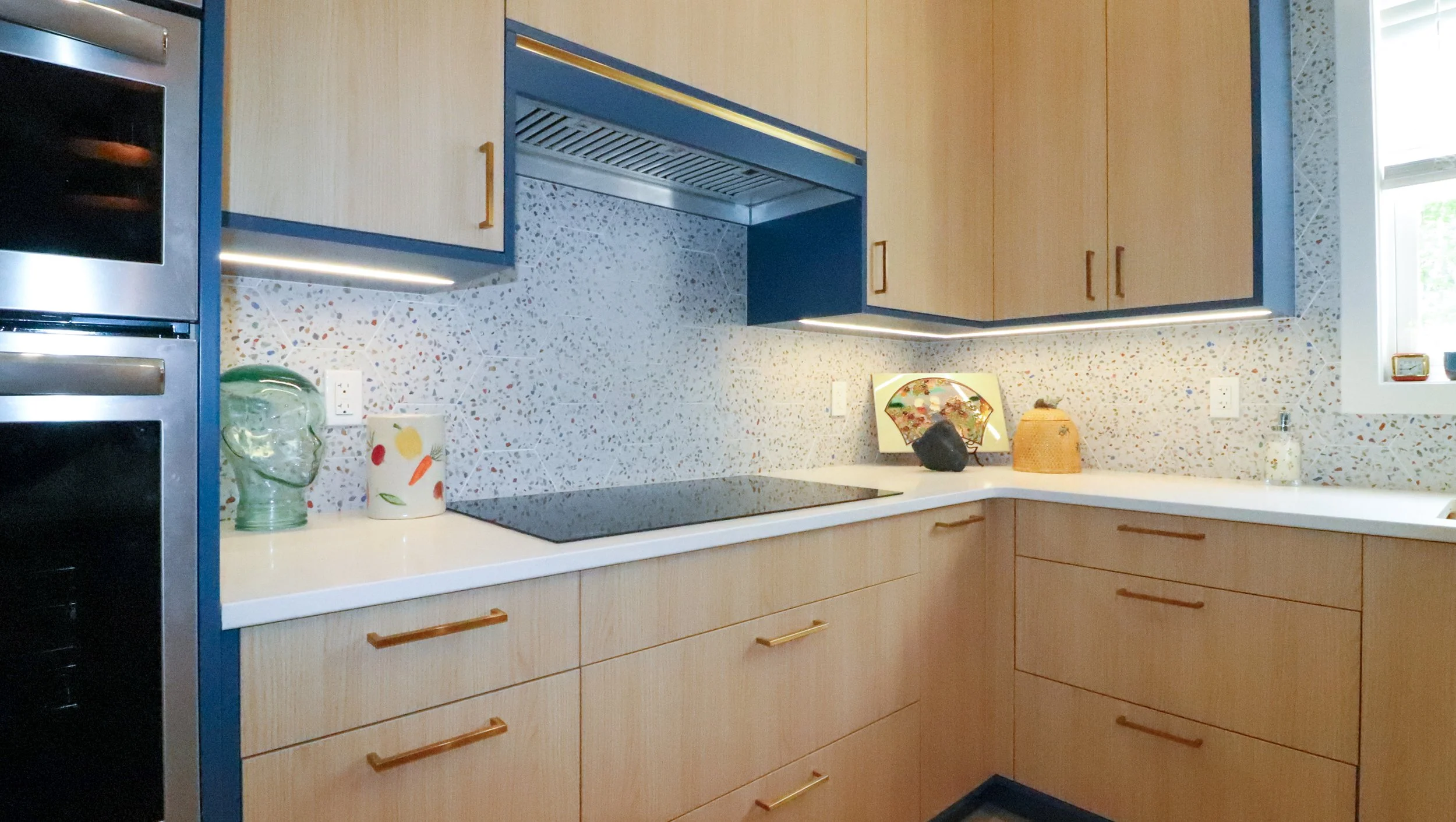 Undercabinet lighting, routed into the bottom panels, washes the hexagonal terrazzo backsplash with even light while keeping the cabinetry lines clean.