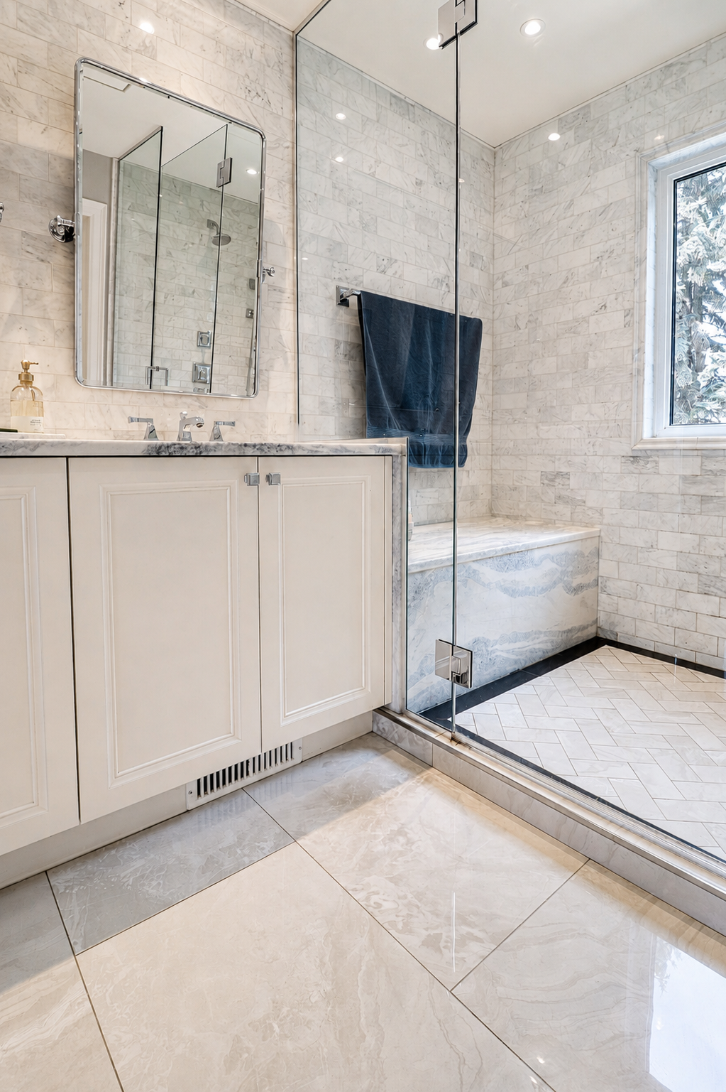 Cloud White bathroom vanity beside marble-lined glass shower and bench.