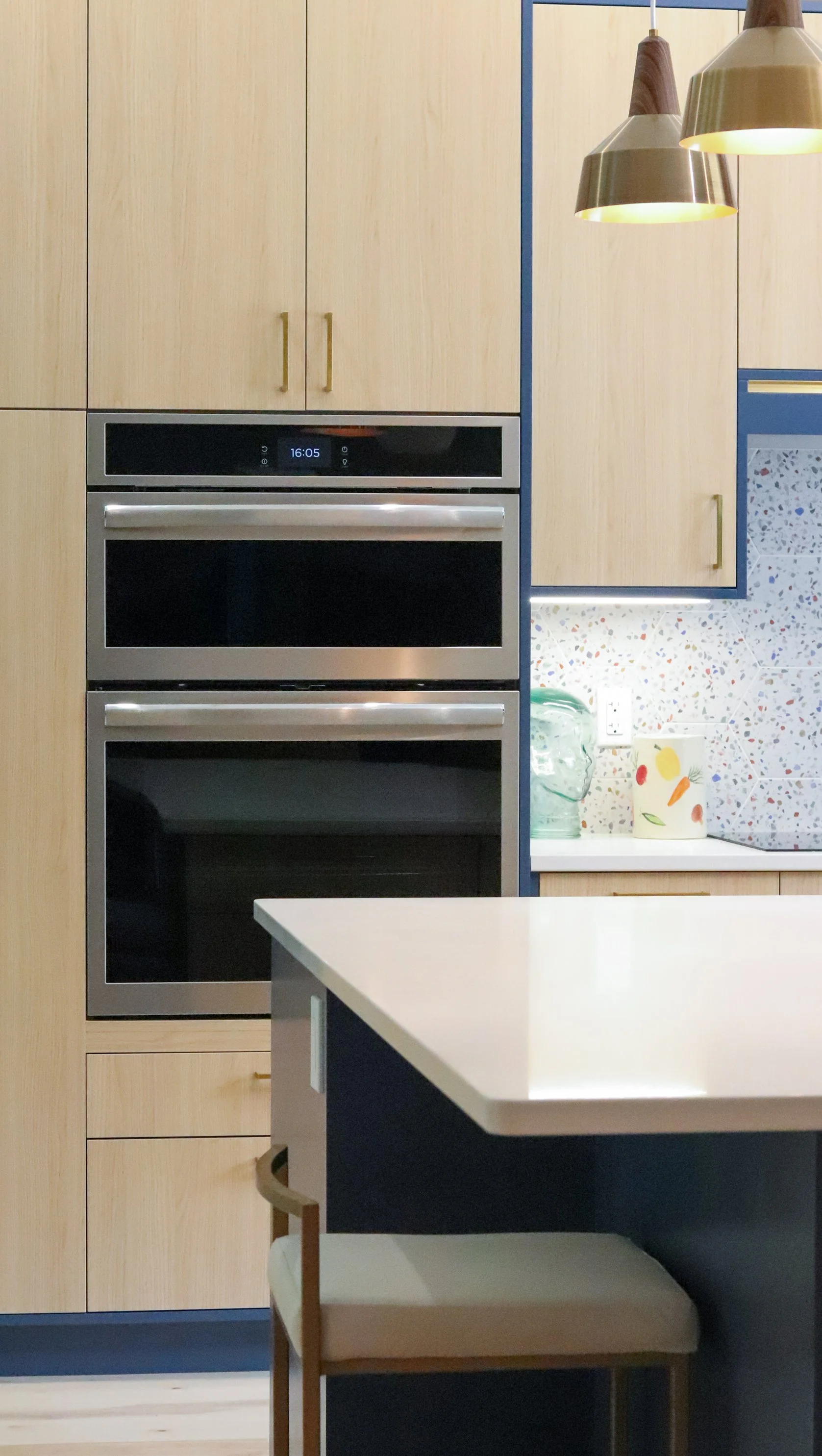 Double wall ovens in Vicenza Oak cabinetry with Kensington Blue surround.