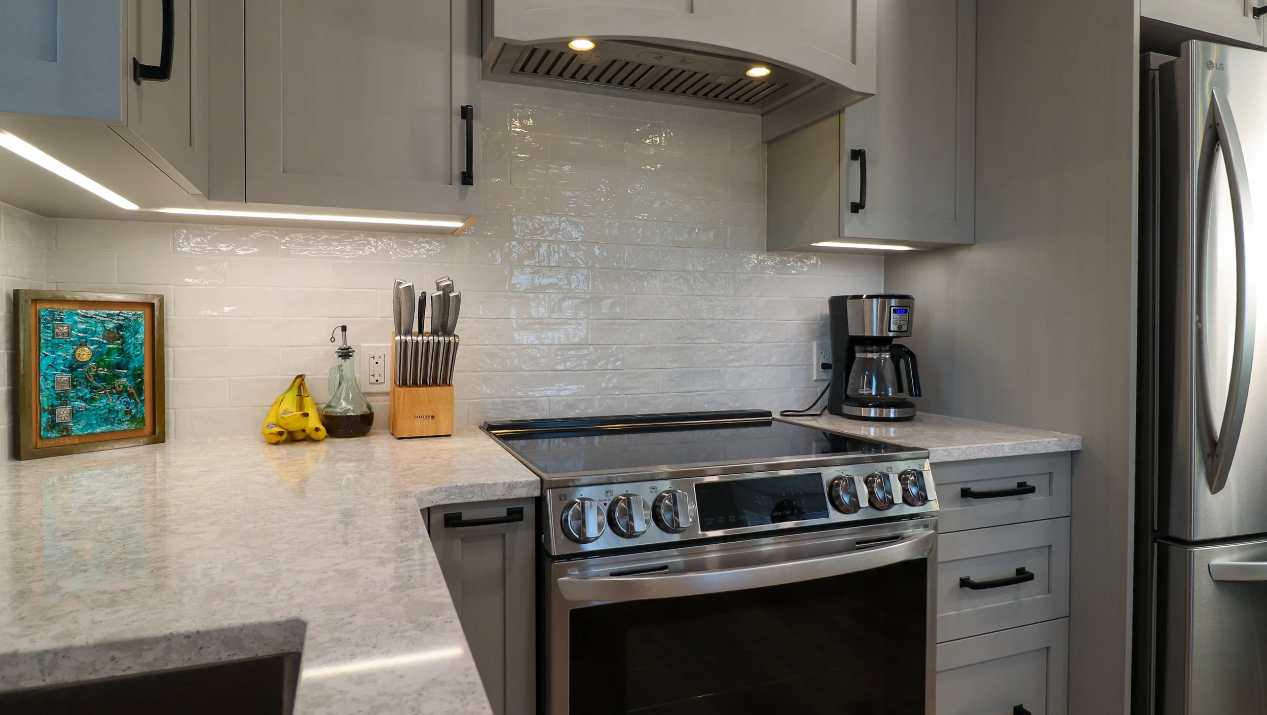 Angled view of stainless range, Stone Grey cabinetry and undercabinet lighting.