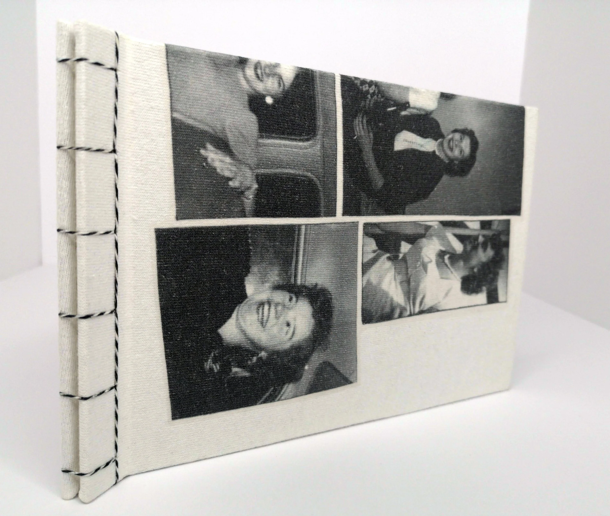 A table displaying various artists' books in a room with shelves filled with colorful books in the background.