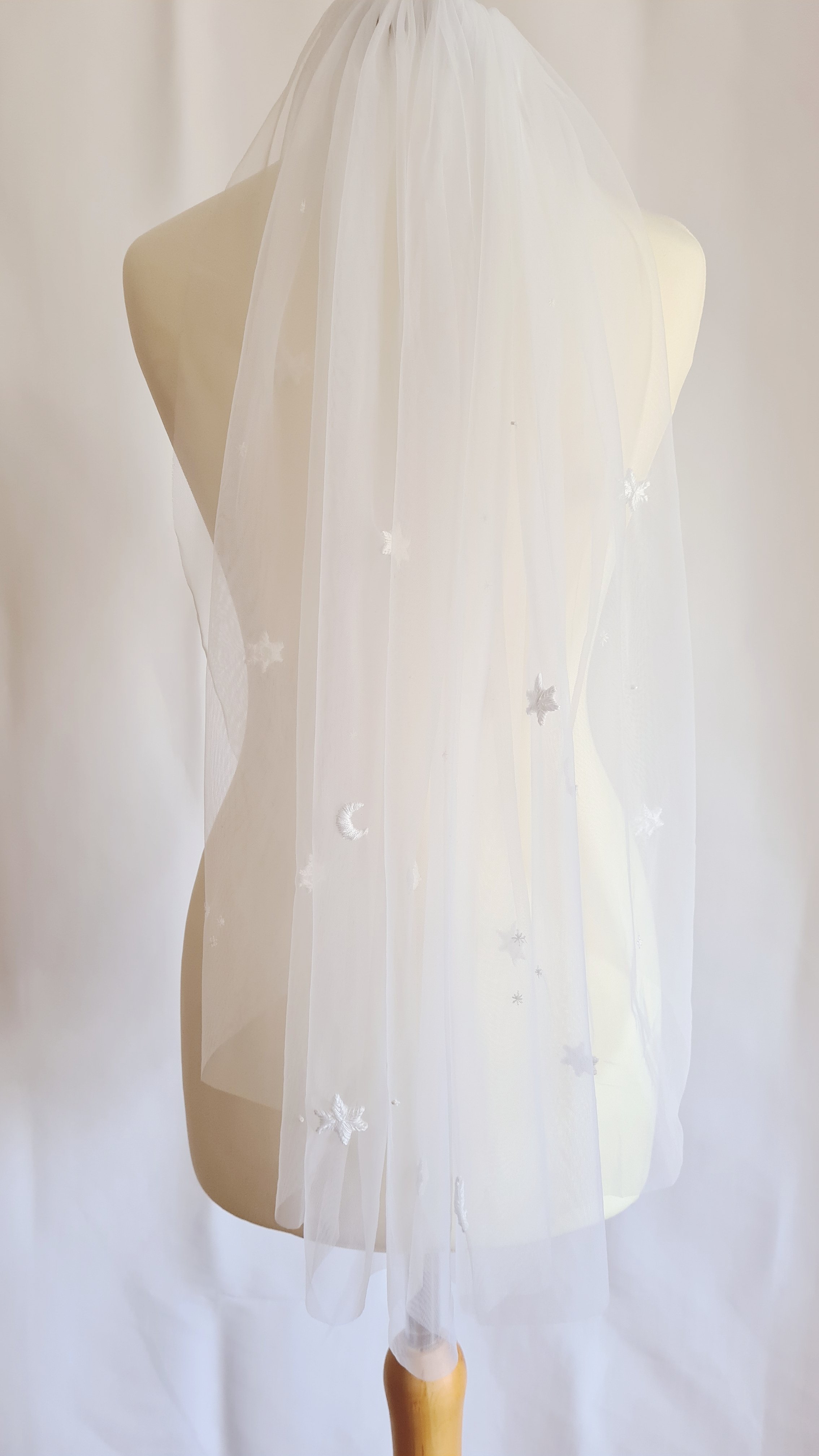 An ivory tulle celestial wedding veil with hand embroidered stars and moons in fingertip length design
