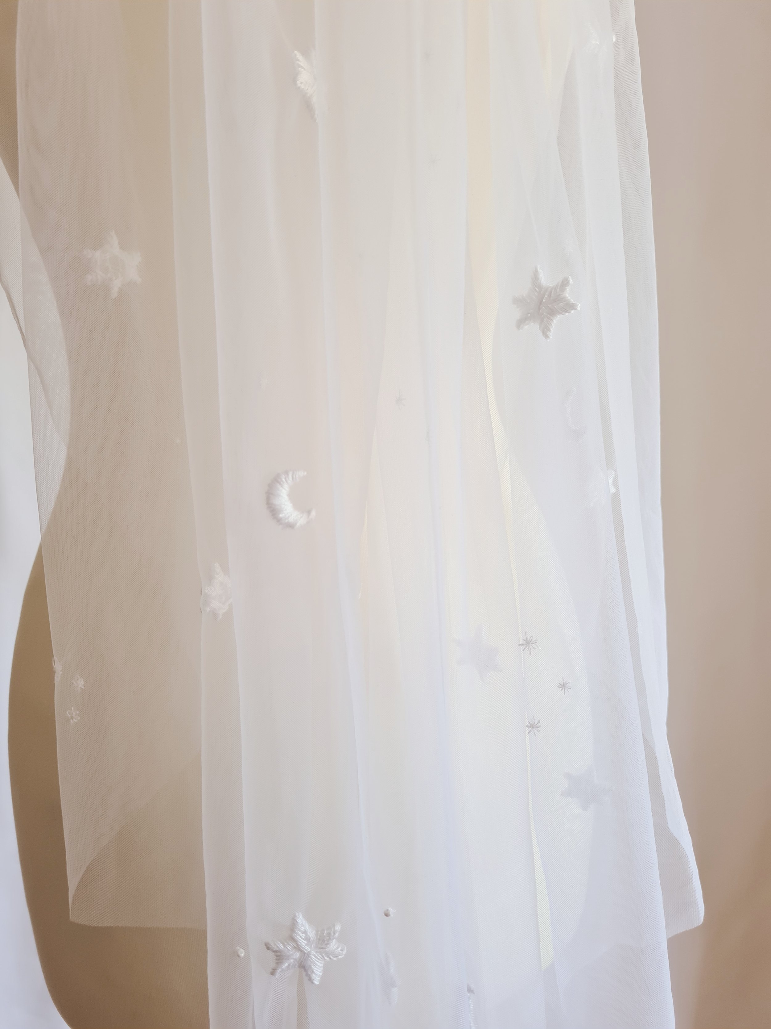 An ivory tulle celestial wedding veil with hand embroidered stars and moons in close up