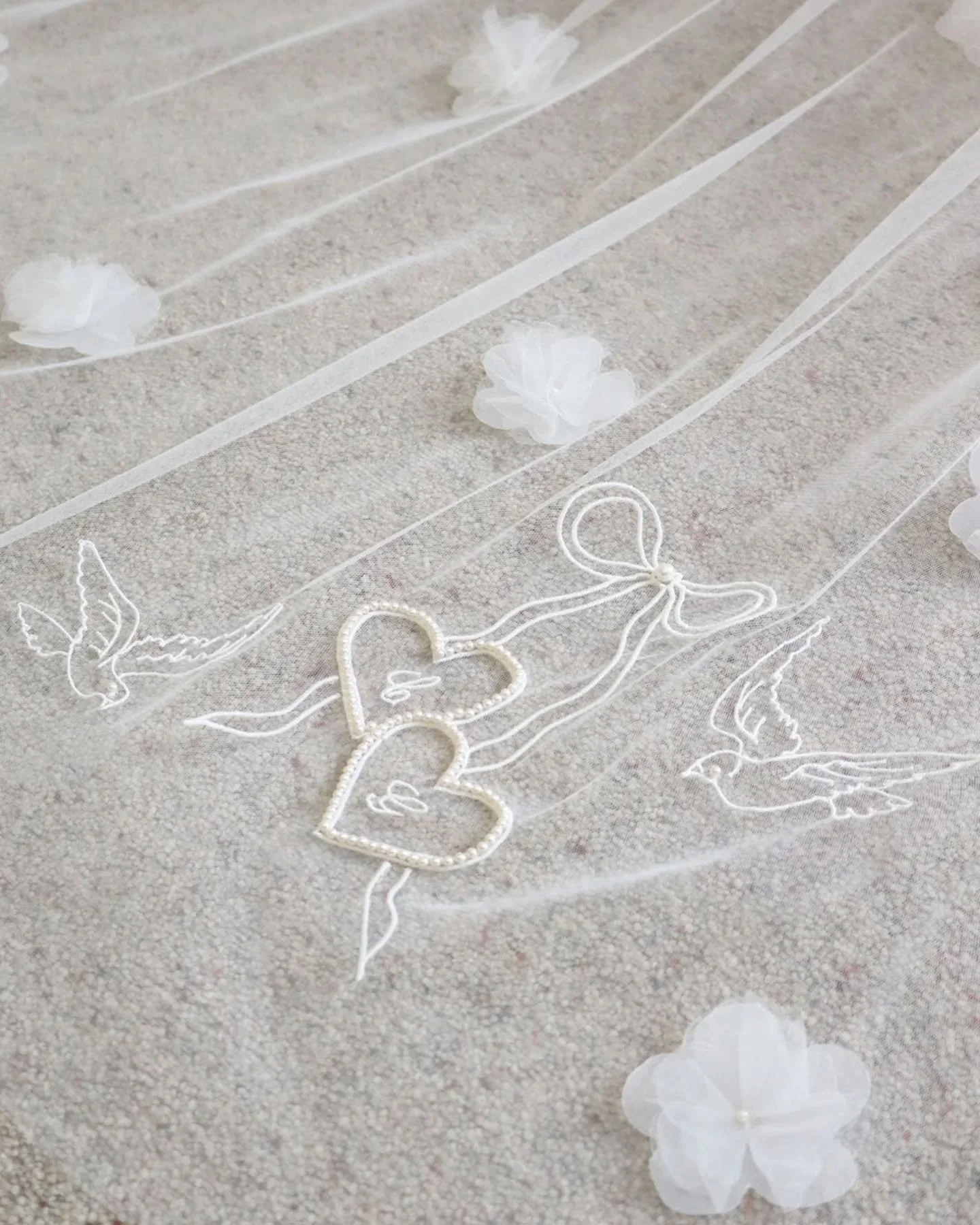 Made with meaning 🤍
This design began as my Pearl Love Hearts with Vintage Bow veil and evolved into something deeply personal. Embroidered initials, little birds, hand beaded pearls and a tiny stitched locket with paw prints to honour the brides ca