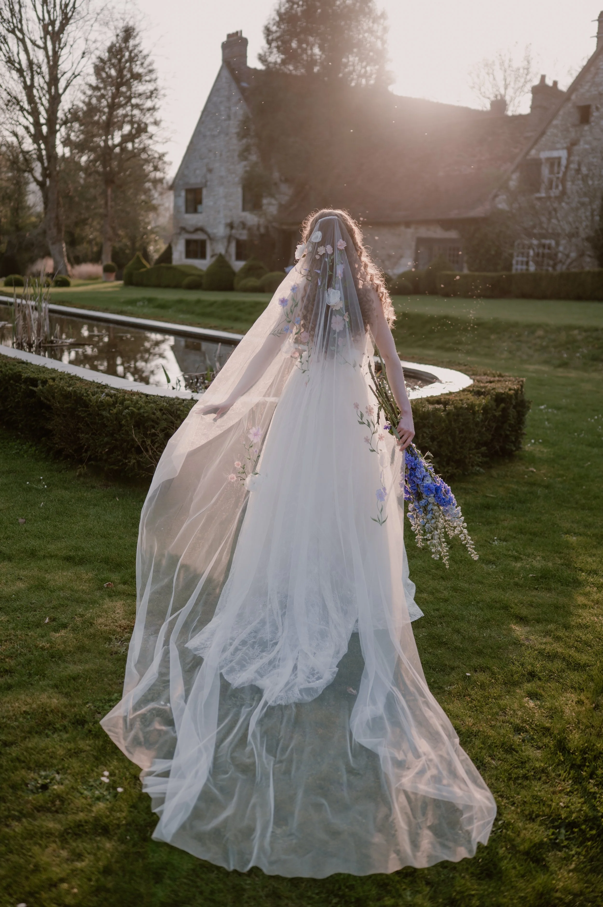 A bride running through a luxury wedding venue in giverny, france. wearing a delicate floral statement wedding veil in long length