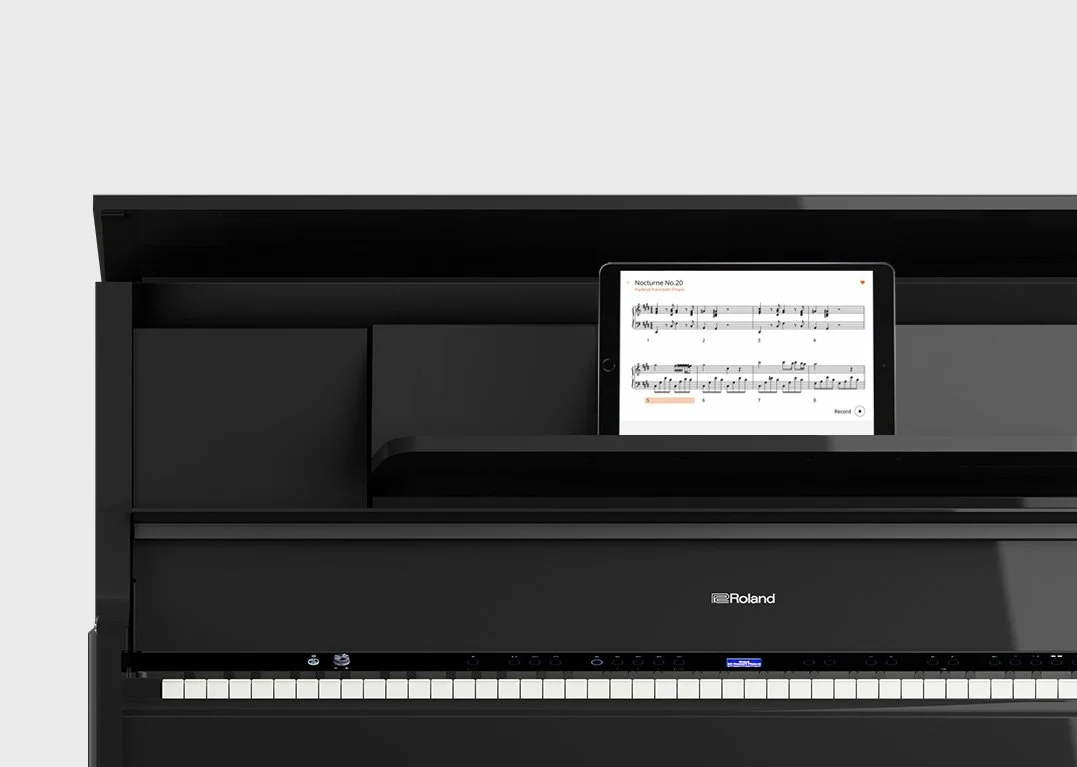 Black digital piano with sheet music displayed on a tablet on top of the keyboard.