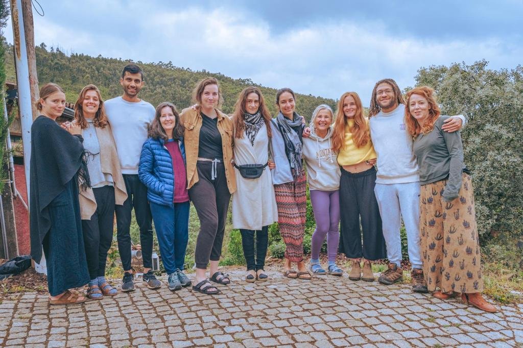 Group of people standing outdoors, smiling, in casual clothing with a scenic natural background.