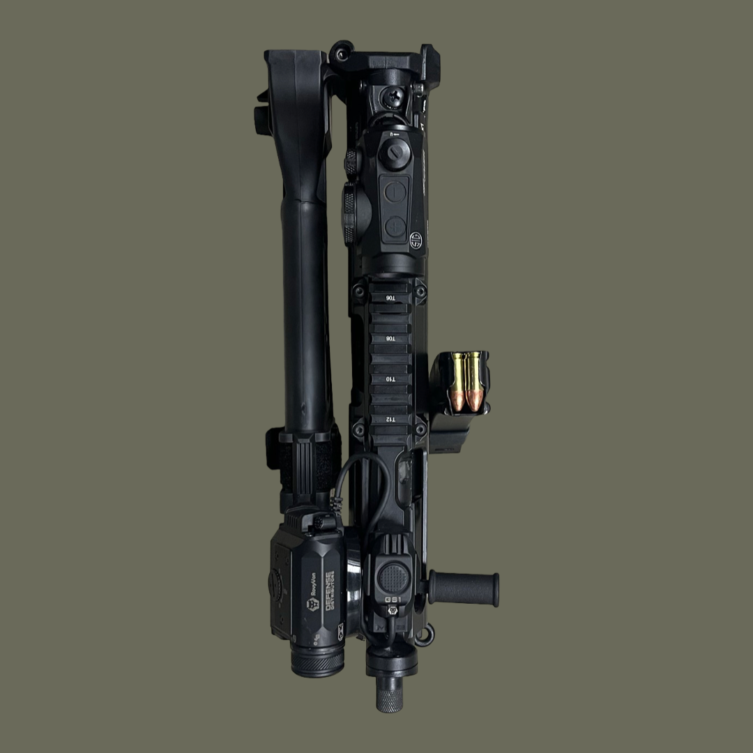 A top-down view of a tactical firearm with accessories, including a scope, ammunition, and various attachments, placed on a plain background.