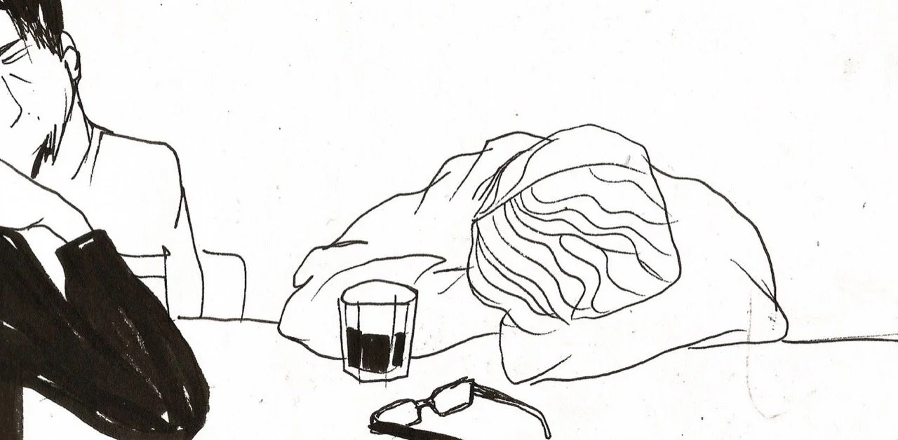 A person resting their head on a table next to a glass of a dark-colored beverage and a pair of glasses, with another person partially visible nearby.
