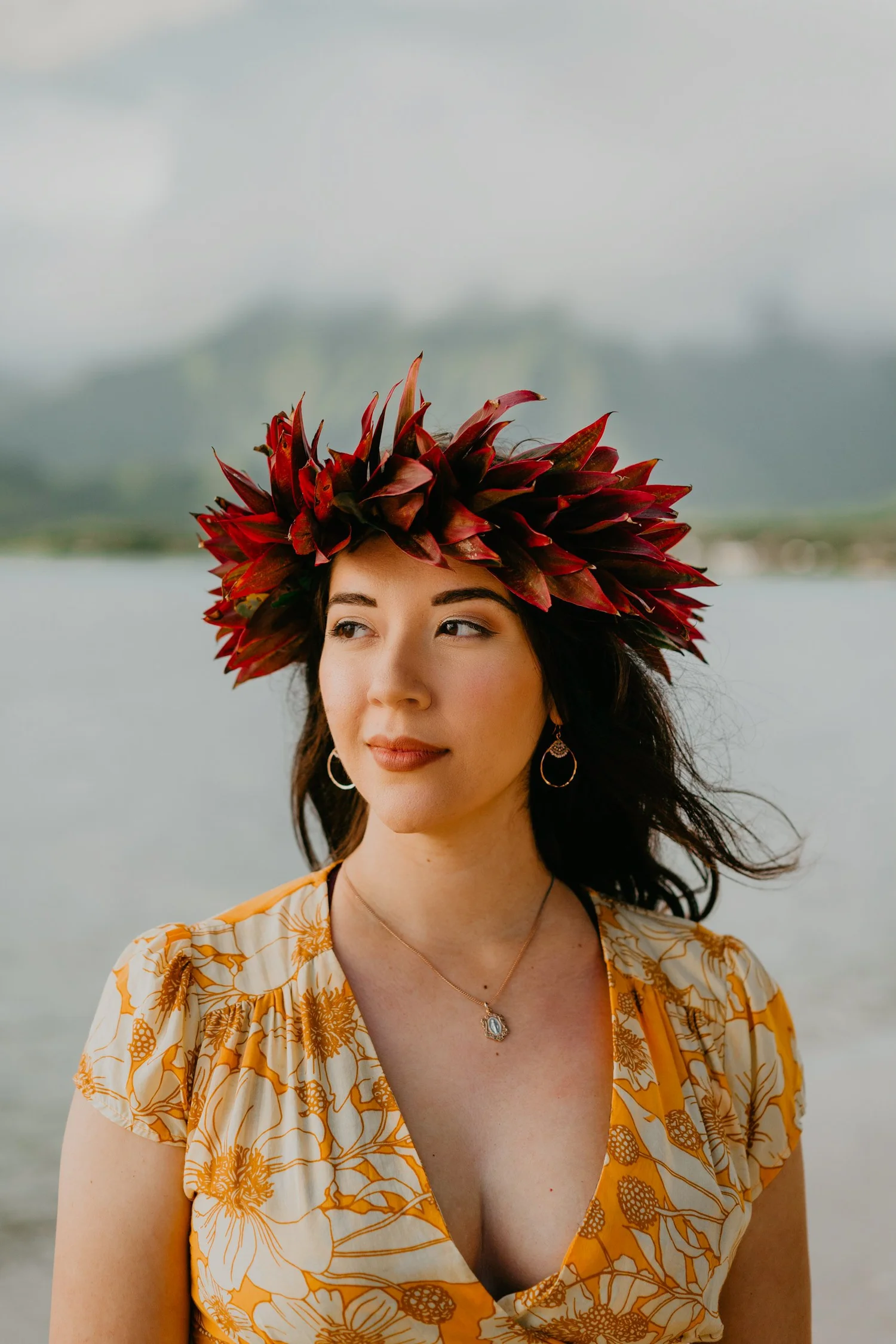 Woman wearing a red leaf headdress standing near water