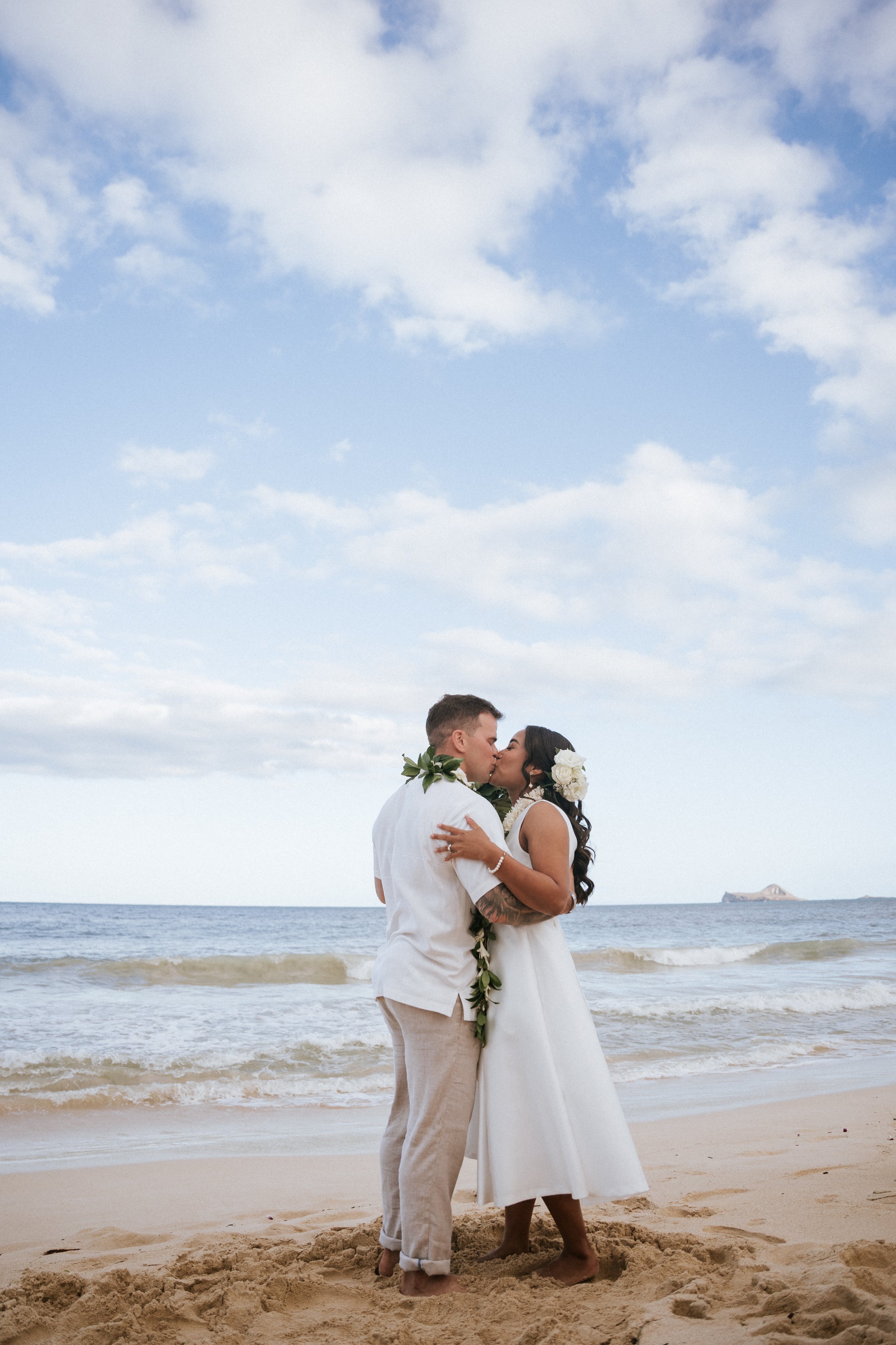 Couple kissing on the beach in wedding attire