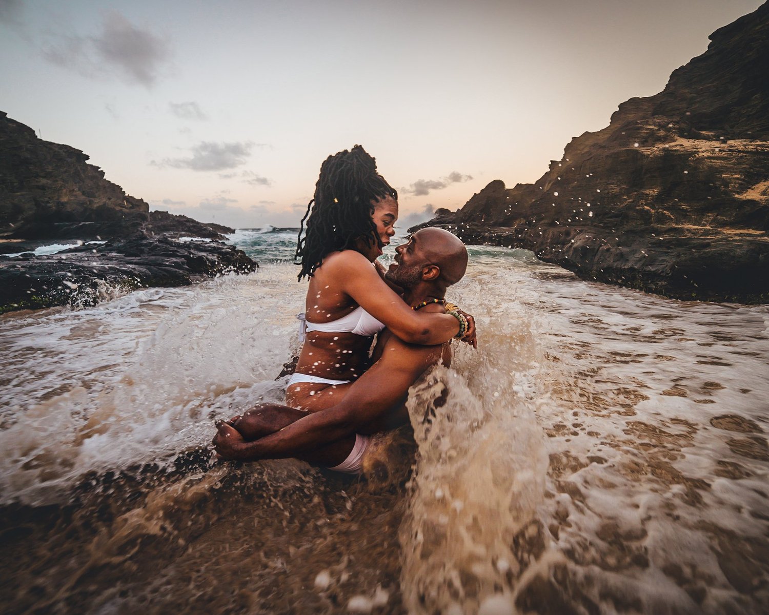 Couple celebrating in the ocean at sunset