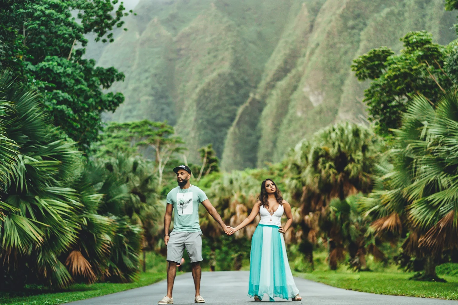 Couple holding hands surrounded by lush greenery and mountains