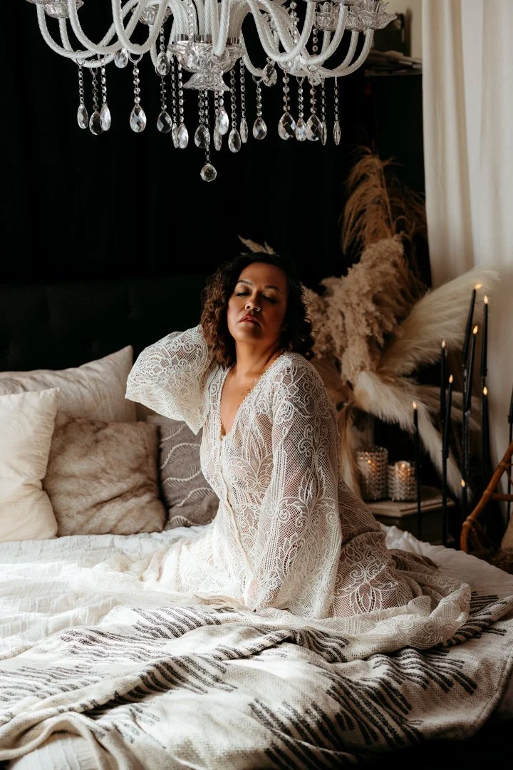 A woman in lace relaxing beneath a crystal chandelier in a softly lit Salt Lake City boudoir studio